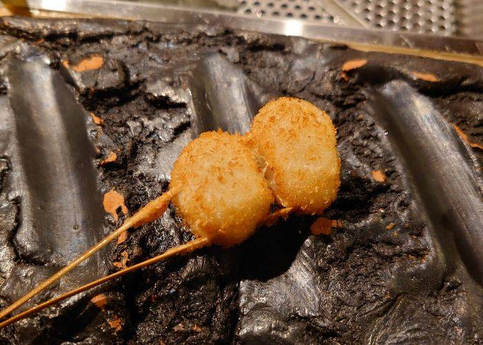 A unique skewer grill at Again in Osaka, with a golden, crispy kushiage skewer.